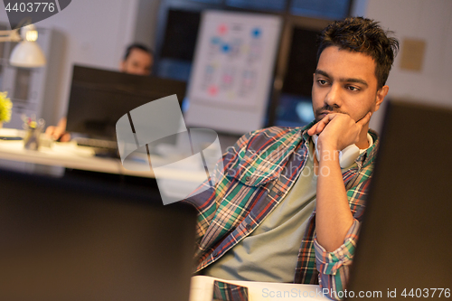 Image of creative man with computer working at night office