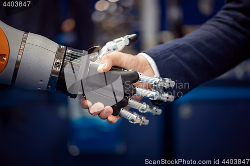 Image of Hand of a businessman shaking hands with a Android robot.