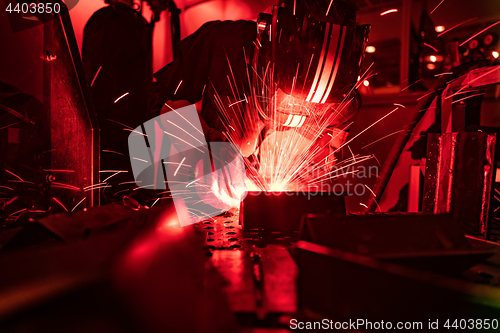 Image of Welder in mask welding metal authentic shooting through red safe