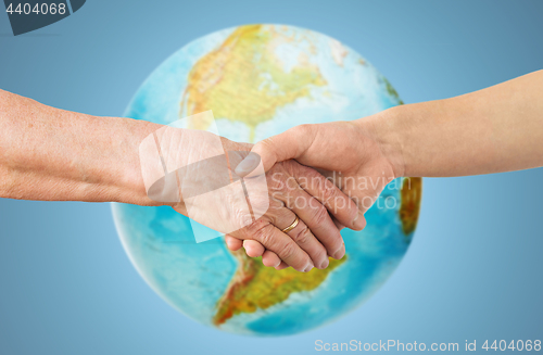 Image of close up of senior and young woman holding hands