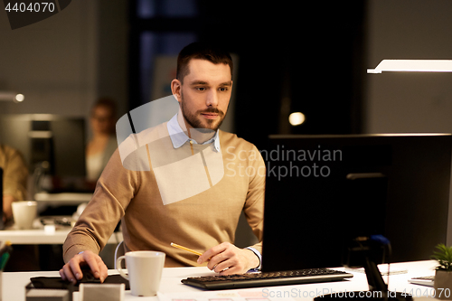 Image of man with computer working late at night office