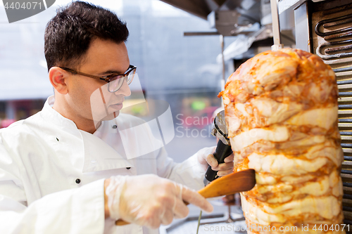 Image of chef slicing doner meat from spit at kebab shop