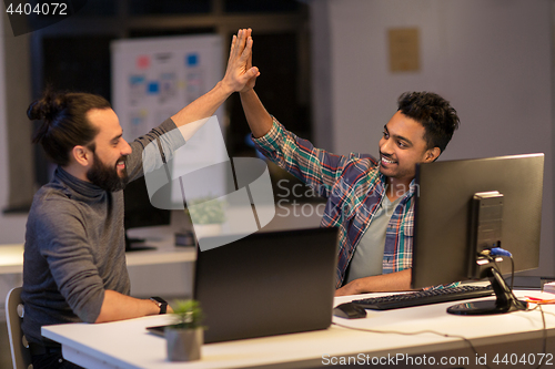 Image of creative team making high five at night office