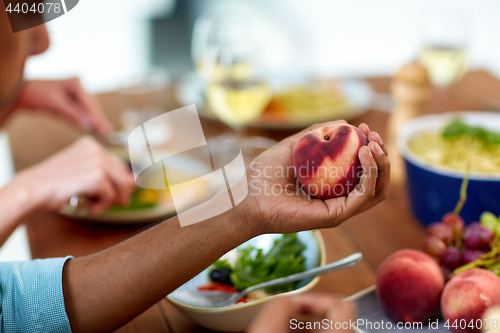 Image of male hand holding peach