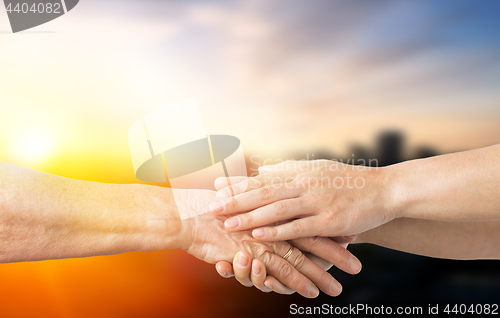 Image of close up of senior and young woman holding hands