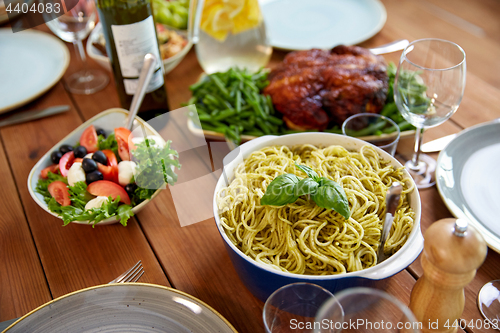 Image of pasta with basil in bowl and other food on table