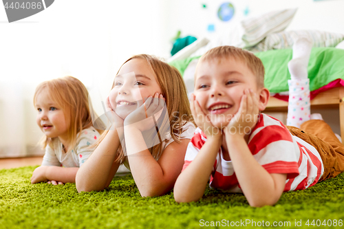 Image of happy little kids lying on floor or carpet