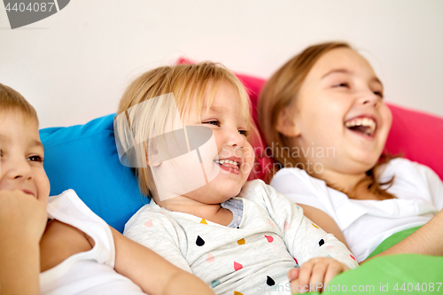 Image of happy little kids having fun in bed at home