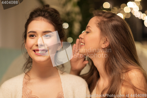 Image of happy female friends gossiping at home