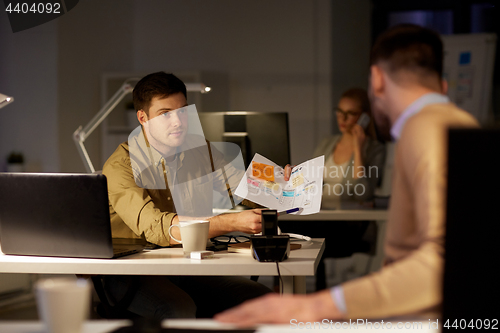 Image of colleagues discussing project late in office