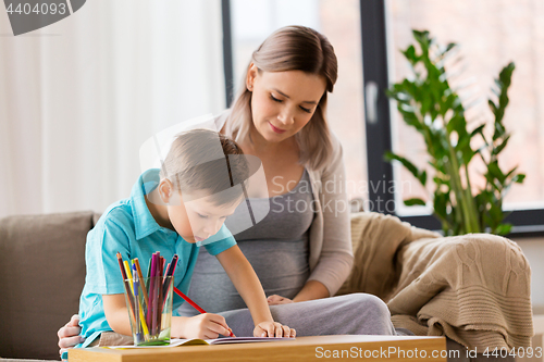 Image of pregnant mother and son with workbook at home