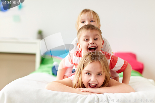 Image of happy little kids having fun in bed at home