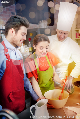 Image of happy couple and male chef cook cooking in kitchen