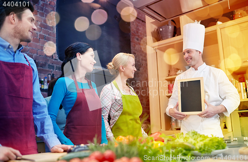 Image of happy friends and chef cook with menu in kitchen