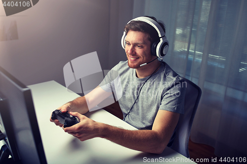 Image of man in headset playing computer video game at home