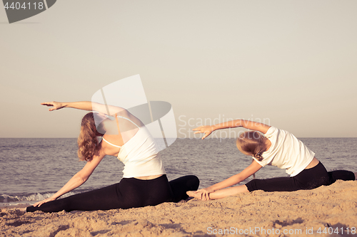 Image of Mother and daughter standing on the beach at the day time.