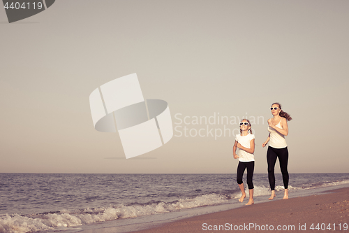 Image of Mother and daughter running on the beach at the day time.