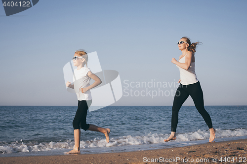 Image of Mother and daughter running on the beach at the day time.