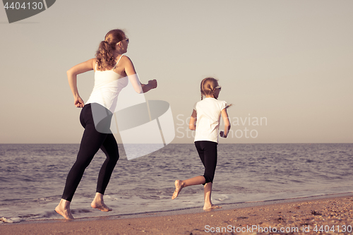 Image of Mother and daughter running on the beach at the day time.