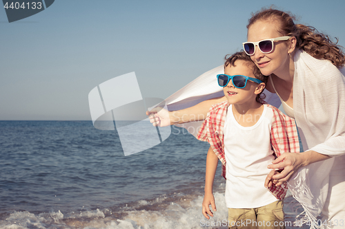 Image of Mother and son standing on the beach at the day time.