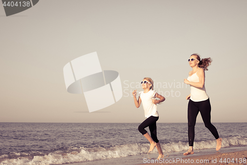 Image of Mother and daughter running on the beach at the day time.