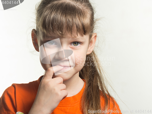 Image of Portrait of a shy girl with finger in mouth on white background