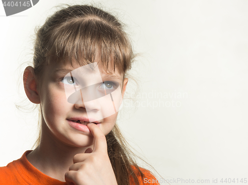 Image of Portrait of a shy girl with a finger in her mouth, looking up thoughtfully
