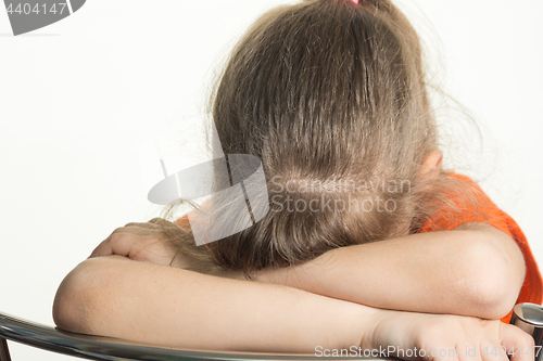 Image of The girl leaned her elbows on the back of the chair and buried herself in folded hands