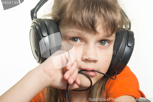 Image of Portrait of a girl in headphones, pensive look in frame