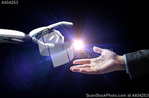Image of robot and human hand flash light over black