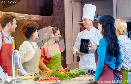 Image of happy friends with chef and tablet pc in kitchen