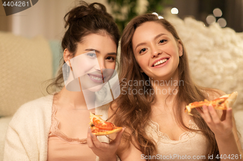 Image of happy female friends eating pizza at home