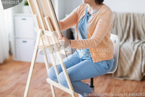 Image of artist with easel drawing picture at art studio