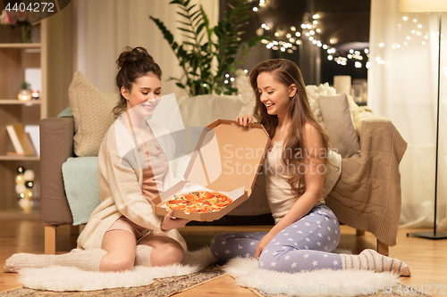Image of happy female friends with pizza at home
