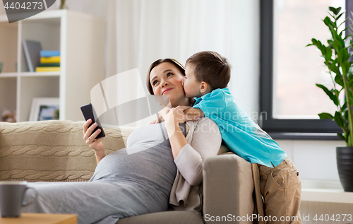 Image of son kissing happy pregnant mother at home