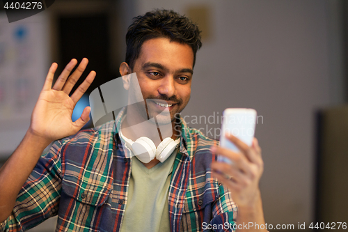 Image of man with smartphone having video call at office
