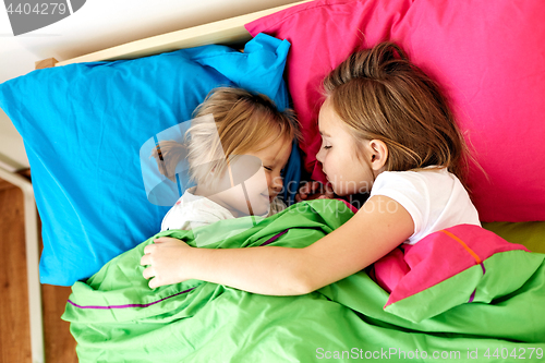 Image of happy little girls sleeping in bed at home