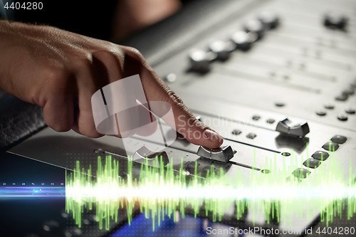 Image of hands on mixing console in music recording studio