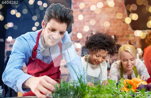 Image of happy friends cooking and decorating dishes