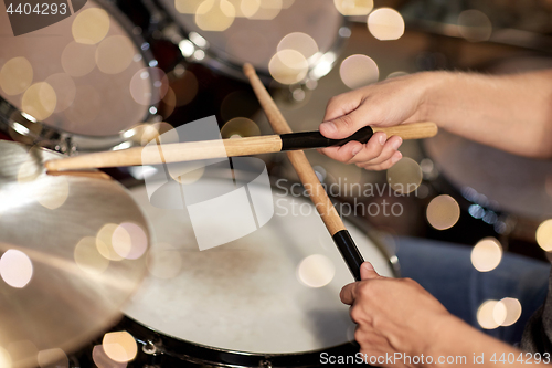 Image of male musician hands with drumsticks at concert