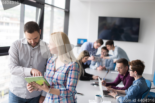 Image of Two Business People Working With Tablet in office