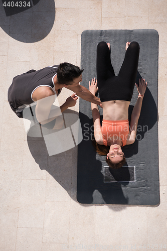 Image of woman with personal trainer doing morning yoga exercises top vie