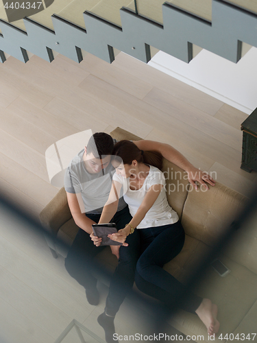 Image of couple relaxing at  home with tablet computers