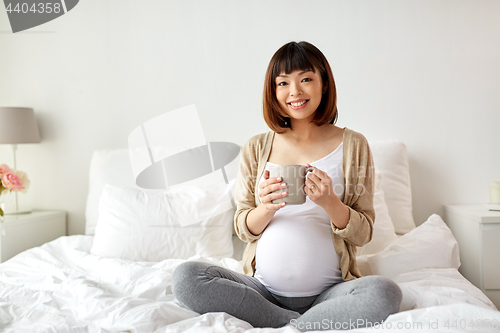 Image of happy pregnant woman with cup drinking tea at home