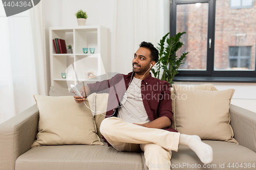 Image of man in earphones listening to music on smartphone