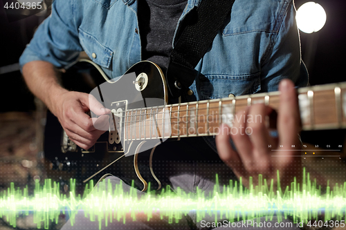 Image of close up of man playing guitar at studio rehearsal