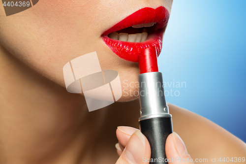 Image of close up of woman applying red lipstick to lips