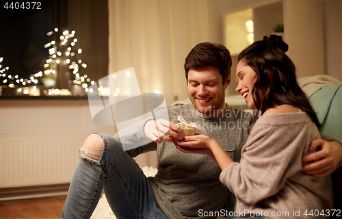 Image of happy couple with gift box at home