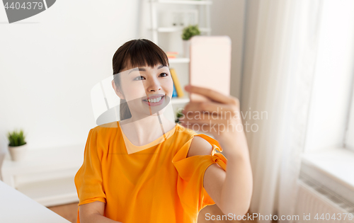 Image of happy asian woman taking selfie by smartphone