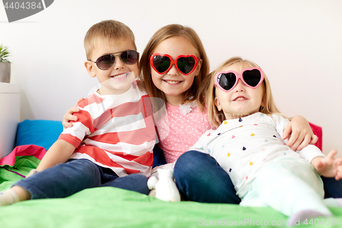 Image of happy little kids in sunglasses at home